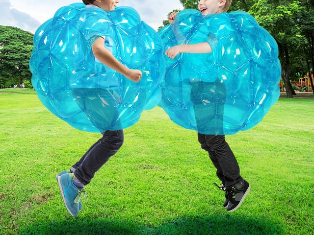 Children running into each other in red and blue bumper balls on a lawn